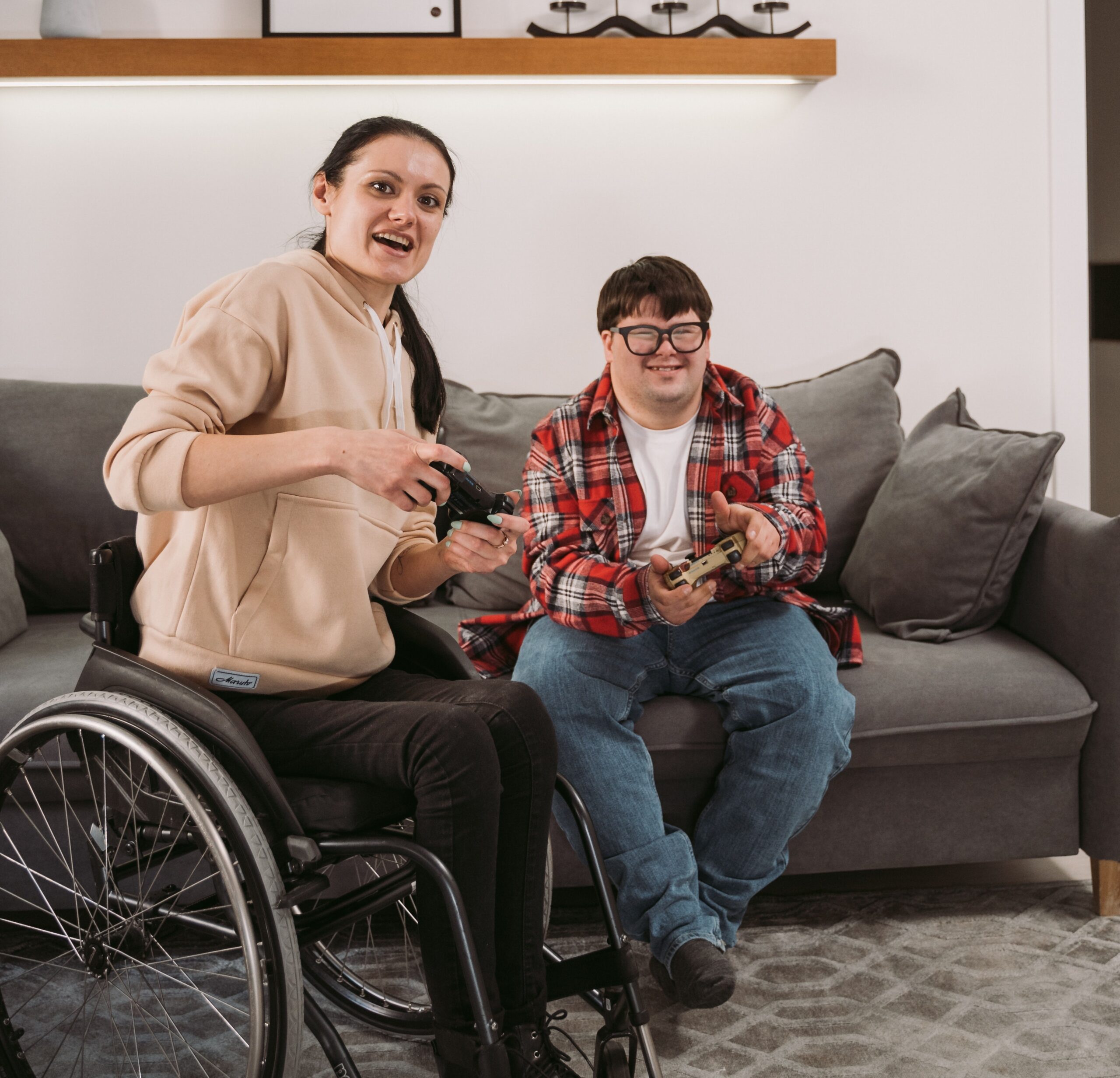women in wheelchair and man on couch play videogames.